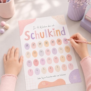 Puede incluir: Un gráfico de cuenta regresiva rectangular impreso en papel con detalles en tonos pastel rosa, naranja y morado. El texto dice In 4 Wochen bin ich Schulkind e incluye óvalos numerados del 1 al 28, algunos marcados con una X con un lápiz rosa.