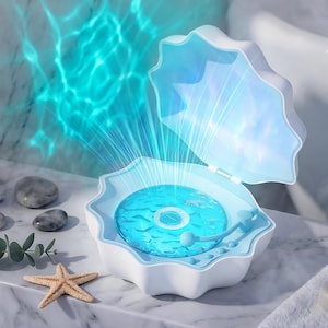 Può includere: Un lettore musicale a forma di conchiglia bianca con interno azzurro. Il dispositivo presenta un disco circolare blu rotante che emette una proiezione di luce blu brillante, imitando le increspature dell'acqua sulle superfici.