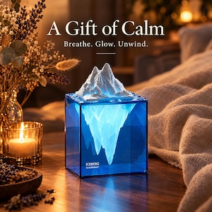 May include: A square blue translucent lamp featuring a white iceberg sculpture on top. The base displays the text ICEBERG GLACIERS&GIFT. The lamp emits a soft light, illuminating the interior structure of the iceberg within the blue cube.