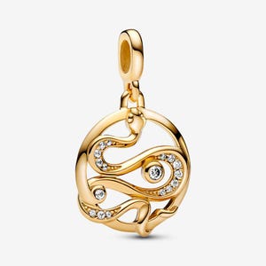 May include: A gold-toned metal pendant featuring a circular frame with a stylised snake coiled inside. The snake body is accented with small, clear, round-cut stones embedded along its length, and a larger clear stone is set within the centre.