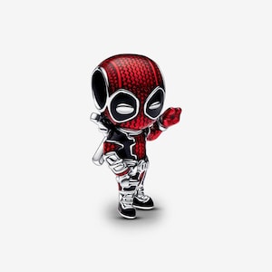 May include: A small, three-dimensional charm shaped like a stylized character with a large head and a red and black suit. The figure features a textured red pattern on the head and torso, black accents, and white eye patches, with one hand raised.