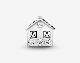 May include: A silver charm shaped like a house with a gabled roof. The front features an embossed bird centered above two square windows with curtains. Below the windows are three stylized flowers with stems and leaves, all rendered in polished silver.