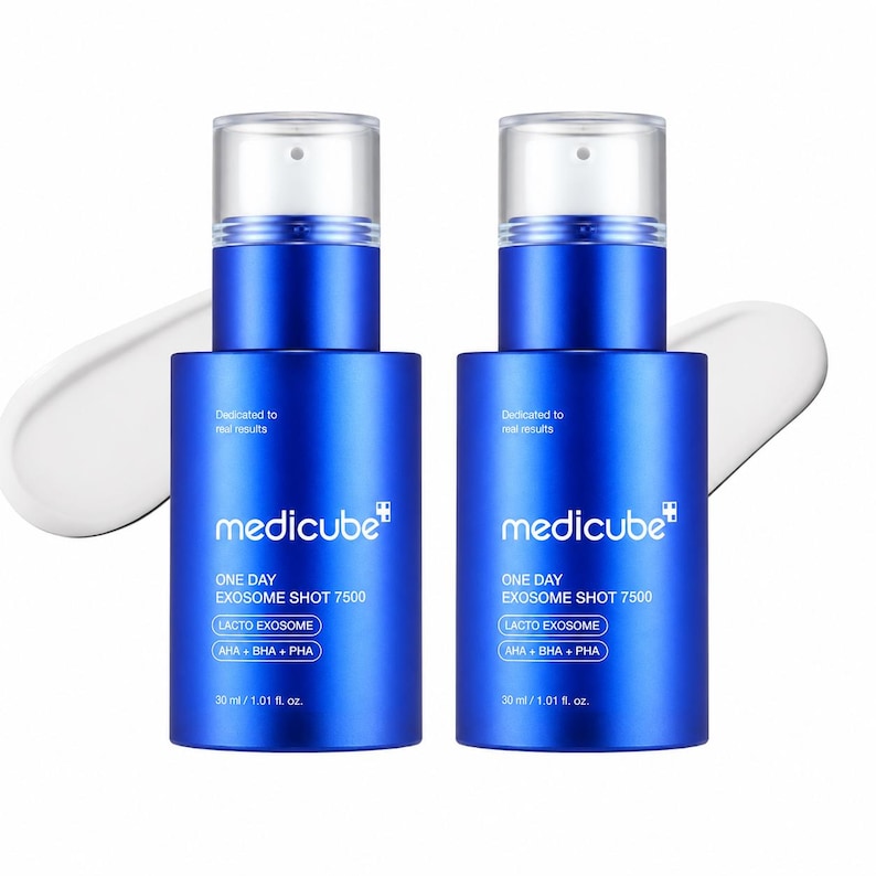 May include: Two identical blue cylindrical skincare bottles with clear pump caps. Each bottle features white text reading medicube, ONE DAY EXOSOME SHOT 7500, LACTO EXOME, AHA + BHA + PHA, and 30 ml / 1.01 fl. oz. A white cream smear is visible behind each bottle.