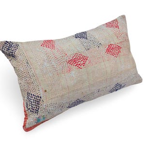May include: A rectangular throw pillow featuring a cream-colored fabric base with visible kantha-style stitching. The surface is decorated with a repeating pattern of small, hand-stitched diamond shapes in alternating red and dark blue thread.