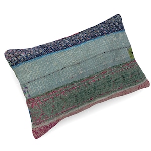 May include: A rectangular throw cushion featuring a patchwork design of woven fabric. The surface displays horizontal bands of colour including dark blue, light blue, muted green, and pink, with a visible textured weave and frayed edges.