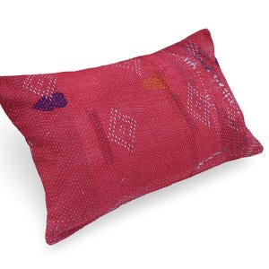 May include: A rectangular throw pillow in a vibrant magenta pink hue, featuring intricate white running stitch embroidery patterns and small, scattered geometric shapes in blue, orange, and purple across the textured fabric surface.