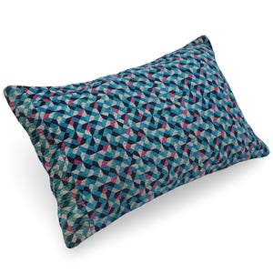 May include: A rectangular throw pillow featuring a repeating geometric pattern of triangles in shades of dark blue, light blue, white, and magenta. The fabric has a textured appearance with a consistent, dense arrangement of small shapes.