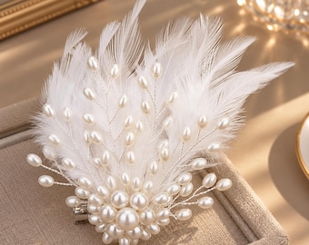 May include: A hair clip featuring a cluster of white faux pearls at the base, with delicate silver-toned wire branches extending outward. The design is accented with soft, white feathers that fan out, creating a layered, textured appearance.