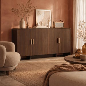 May include: A dark brown wooden sideboard featuring four cabinet doors with vertical gold-toned metal handles. The rectangular furniture piece has rounded corners and is supported by a low base, providing a flat surface for decorative items.