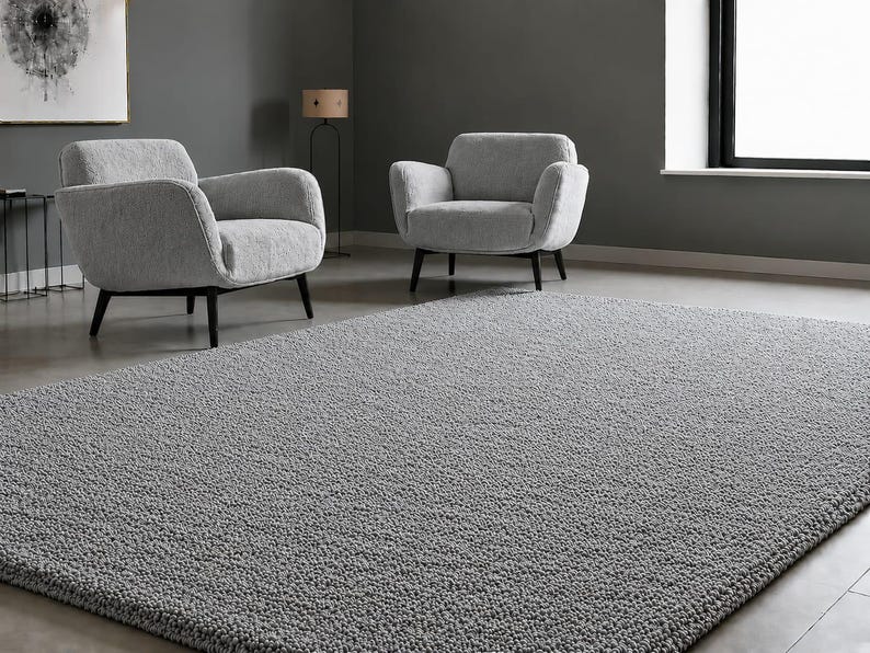 May include: A rectangular area rug with a thick, textured, grey shag pile surface. The rug features a dense, looped construction that creates a soft, uneven appearance across the entire top surface, providing a consistent grey colour throughout.
