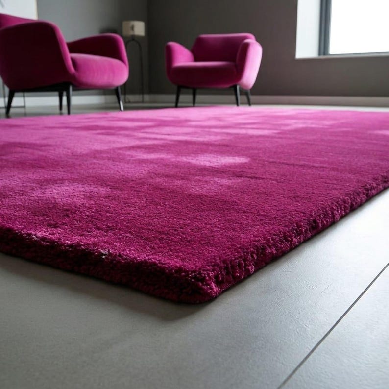 May include: A rectangular area rug with a deep magenta, plush, high-pile texture. The rug features a solid, uniform colour throughout its surface, showcasing a thick, soft material that covers the floor area in a consistent, vibrant shade of pink.