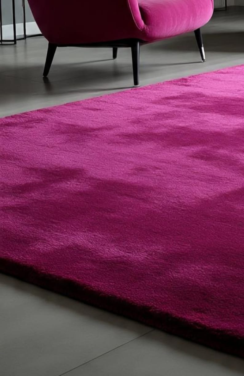 May include: A plush, deep magenta area rug with a thick, soft-textured pile. The rug features a solid, vibrant fuchsia colour that covers the entire surface, providing a dense and uniform appearance across the rectangular floor covering.