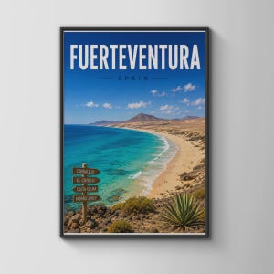 May include: A framed travel poster featuring the text FUERTEVENTURA SPAIN above a coastal landscape. The scene shows a turquoise ocean meeting a sandy beach, with a wooden signpost pointing to Corralejo, El Cotillo, Costa Calma, and Morro Jable.