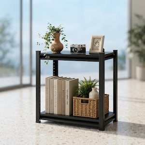 May include: A black two-tier metal shelf unit. The top shelf holds a tan ceramic vase with a trailing green plant, a black camera, and a framed picture. The bottom shelf contains a row of five books and a woven basket holding a green plant.