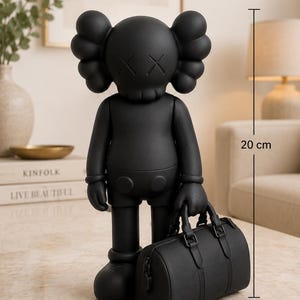 May include: A matte black collectible character figure featuring iconic X-shaped eyes and rounded ears, standing 20 cm tall. The figure holds a matching black duffel bag with a textured surface, structured handles, and a side zipper detail in its hand.