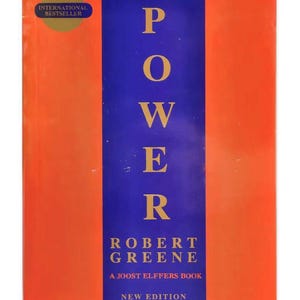 May include: A book titled The Concise 48 Laws of Power by Robert Greene, a Joost Elffers book, new edition. The cover features a vertical blue stripe centered on an orange background with yellow text and a gold International Bestseller seal.
