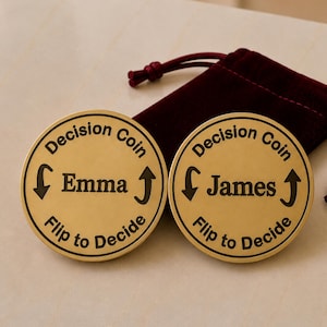 May include: Two circular gold-toned metal decision coins featuring black engraved text. Each coin displays the words Decision Coin and Flip to Decide, with arrows pointing up and down. One coin is personalized with the name Emma, and the other with James.