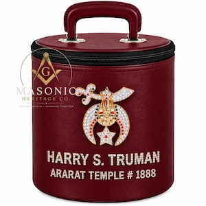 May include: A cylindrical burgundy carrying case with a top handle and a black zipper. The front features a gold-toned Shriners emblem with rhinestones, and the text HARRY S. TRUMAN ARARAT TEMPLE # 1888 in rhinestone lettering.