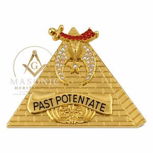 May include: A gold-tone triangular emblem featuring a brick pattern, a central sphinx figure, and a crescent shape adorned with iridescent crystals. A red crystal-encrusted scimitar sits at the top, and a banner reads PAST POTENTATE in black text.
