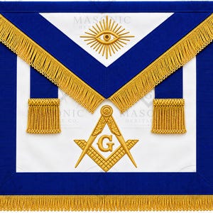 Könnte beinhalten: Eine weiße Freimaurerschürze mit blauem Rand und goldener Fransenborte. Das Design umfasst ein gesticktes goldenes Auge mit Strahlen oben sowie ein goldenes Winkel- und Zirkel-Emblem mit dem Buchstaben G in der Mitte und zwei goldenen Quasten.