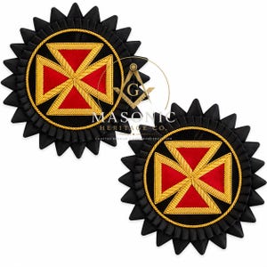 May include: Two circular black rosettes featuring a central red cross with gold embroidered borders. Each rosette has a pleated black fabric edge and a gold rope trim encircling the cross. The Masonic Heritage Co. logo is overlaid in the center.