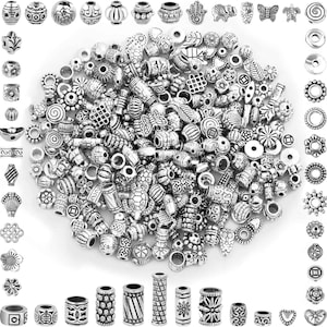 May include: A large collection of assorted silver-toned metal beads in various shapes and sizes, including round, cylindrical, and flat designs. The beads feature intricate embossed patterns, such as flowers, animals, geometric shapes, and symbols.