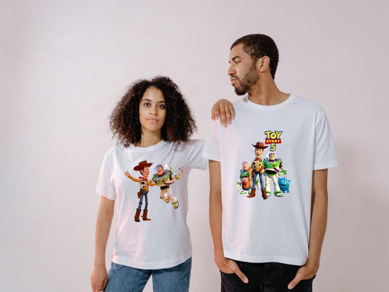 May include: Two white short-sleeved t-shirts featuring Toy Story 5 graphic prints. One shirt displays Woody and Buzz Lightyear, while the other features a group of characters including Woody, Buzz Lightyear, Mr. Potato Head, and Ducky with the Toy Story 5 logo.