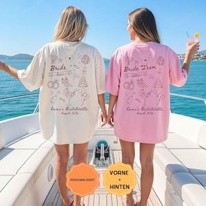 Könnte beinhalten: Zwei Oversize-T-Shirts, eines in Creme und eines in Rosa, mit dunkelbraunen Strichzeichnungen von Hochzeitssymbolen wie Ringen, High Heels, einer Torte und Champagner. Das cremefarbene Shirt zeigt Bride Emma, das rosa Shirt Bride Team, Emma's Bachelorette August 2026.