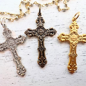 Peut inclure: Trois pendentifs en forme de croix ornés d'argent, d'or et de bronze avec des motifs complexes. Les croix sont suspendues à un collier à chaîne.