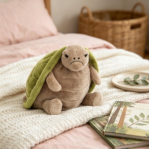 May include: A plush turtle toy featuring a soft, light brown body with a textured, rounded green shell. The stuffed animal has a small head with dark eyes, a stitched mouth, and short limbs, designed with a smooth, velvety fabric texture throughout.