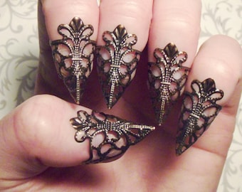 Puede incluir: Conjunto de cinco anillos de punta de dedo adornados, de color bronce, con un diseño puntiagudo en forma de garra. Cada anillo presenta un delicado y complejo patrón de filigrana.