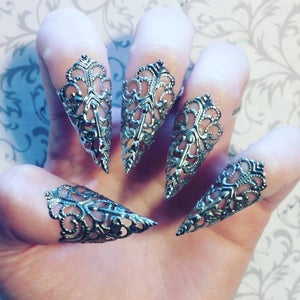 May include: Five silver filigree claw rings. The rings are pointed and have a delicate, intricate design.