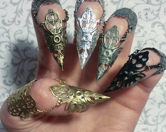 Op de afbeelding: Set van zes vinger ringen met een puntig, klauw-achtig ontwerp. De ringen zijn gemaakt van metaal en hebben verschillende afwerkingen, waaronder zilver, goud en zwart.