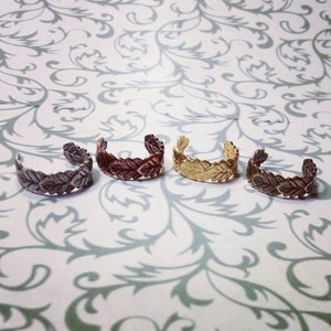 Puede incluir: Cuatro pendientes de oreja en diferentes acabados metálicos: plata, cobre, oro y bronce. Cada pendiente presenta un delicado diseño de hojas.