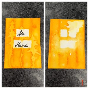 Op de afbeelding: Twee rechthoekige kaarten met een levendige oranje en gele aquarelachtergrond. De linkerkaart bevat silhouetten van drie dennenbomen en twee witte rechthoekige labels met de zwarte handgeschreven tekst "für" en "Mama". De rechterkaart toont twee lege witte rechthoekige vlakken.