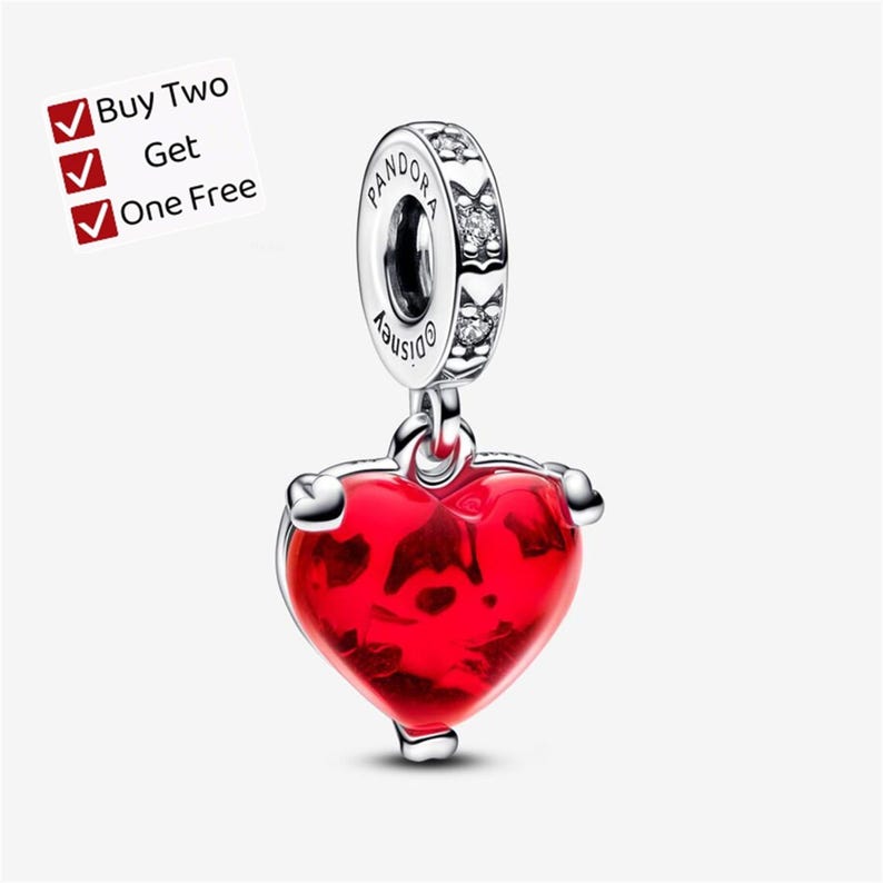 May include: A silver charm featuring a bright red heart pendant suspended from a circular bail. The bail is engraved with the text Pandora and Disney, and is accented with small clear stones. A white label displays the text Buy Two Get One Free.