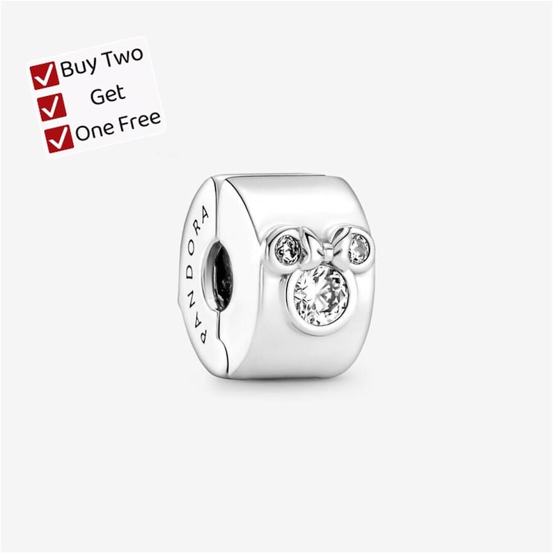 May include: A silver charm bead featuring a polished finish and the engraved text PANDORA on the side. The front displays a stylized mouse head silhouette accented with three clear, round-cut stones. A white label reads Buy Two Get One Free.