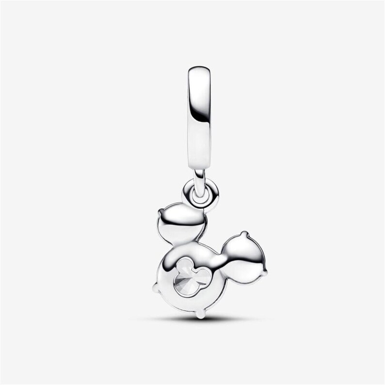 May include: A polished silver dangle charm featuring a stylized silhouette of a mouse head with rounded ears. The charm includes a small circular cutout in the center and is attached to a smooth, vertical silver bail for easy attachment to jewelry.