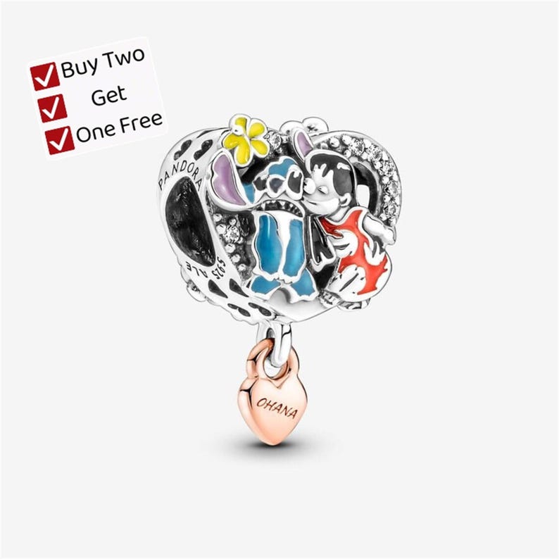 May include: A silver heart-shaped charm featuring a blue and black alien character and a girl in a red dress, accented with a yellow flower and clear stones. A small rose-gold heart dangle hangs below, engraved with the word OHANA.