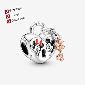 May include: A silver heart-shaped padlock charm featuring engraved images of Mickey and Minnie Mouse, with the text "YOU & ME" and "PANDORA S925" visible. A small rose-gold colored key charm with a bow detail is attached to the padlock by a chain.