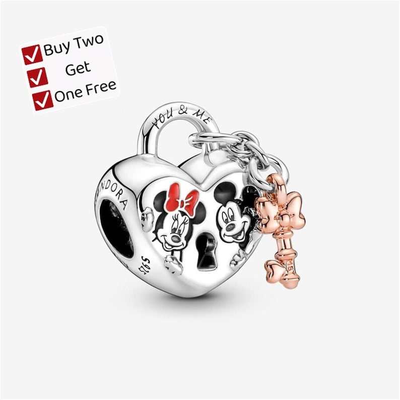 May include: A silver heart-shaped padlock charm featuring engraved images of Mickey and Minnie Mouse, with the text "YOU & ME" and "PANDORA S925" visible. A small rose-gold colored key charm with a bow detail is attached to the padlock by a chain.