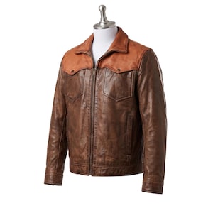May include: A brown leather jacket featuring a lighter tan leather yoke across the shoulders and chest. The jacket includes a full-length front zipper, a pointed collar, two chest pockets with buttoned flaps, and long sleeves with cuffs.