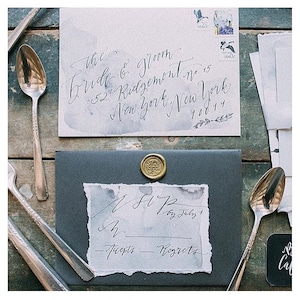 Calligrafia della suite di inviti di nozze di carta strappata a mano organica terrosa con sfondo splatter ad acquerello