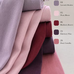 May include: A stack of five fabric bolts in shades of lavender, light pink, deep red, dark purple, and dusty rose. The text labels include 04 Lavender Meadow, 05 Peony Bloom, 06 Blackberry Reserve, 23 Elderberry Wine, and 29 Dusty Camellia.