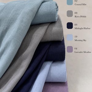 May include: A stack of folded fabric in five distinct colors with a corresponding color chart on the right. The colors are labeled 02 Coastal Mist, 08 River Pebble, 09 Midnight Harbor, 19 Morning Sky, and 04 Lavender Meadow in a list format.