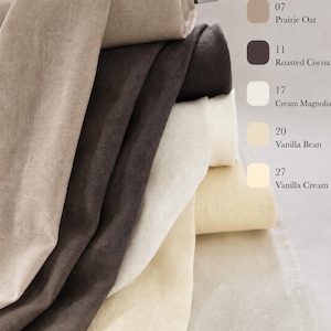May include: A stack of fabric rolls in various neutral shades including Prairie Oat, Roasted Cocoa, Cream Magnolia, Vanilla Bean, and Vanilla Cream. Each roll is labeled with its corresponding color name and number, showcasing the texture of the fabric.