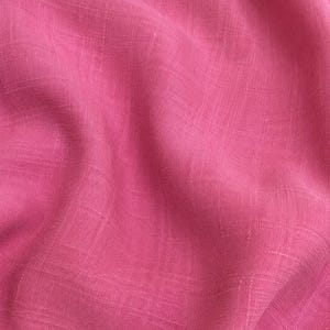 Op de afbeelding: Een levendige wilde pioenroos roze stof met een zichtbare geweven textuur met horizontale en verticale draden. Het materiaal vertoont zachte plooien en draperingen over het oppervlak. De tekst 03 Wild Peony Pink is onderaan in het wit gedrukt.