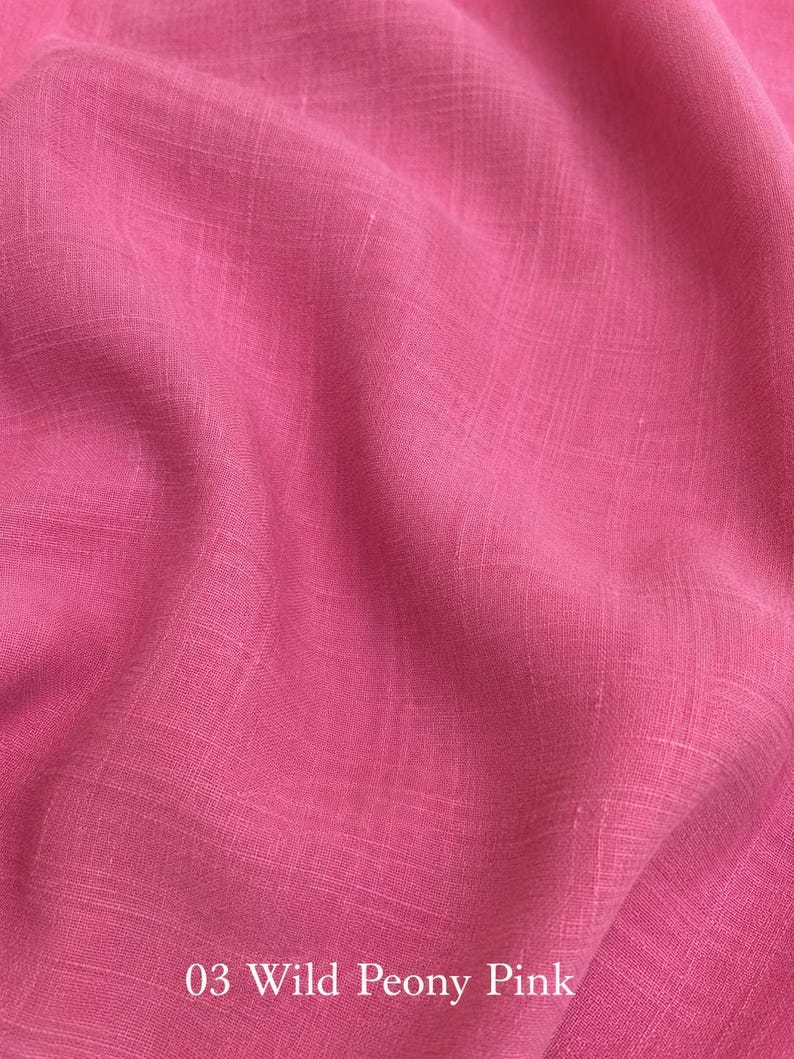 Op de afbeelding: Een levendige wilde pioenroos roze stof met een zichtbare geweven textuur met horizontale en verticale draden. Het materiaal vertoont zachte plooien en draperingen over het oppervlak. De tekst 03 Wild Peony Pink is onderaan in het wit gedrukt.