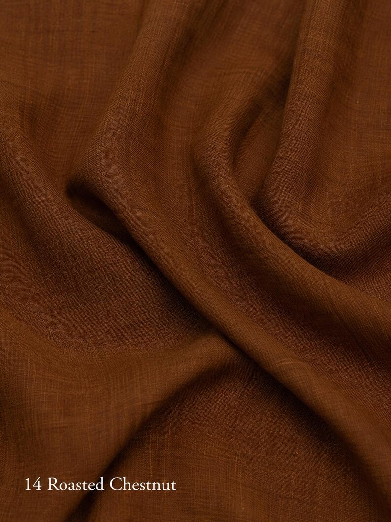 Op de afbeelding: Een stuk stof in een diepe, rijke bruine tint, gelabeld als 14 Roasted Chestnut. Het materiaal heeft een zichtbaar, fijnmazig weefsel met zachte, vloeiende plooien die natuurlijke schaduwen en highlights cre&euml;ren op het getextureerde oppervlak.