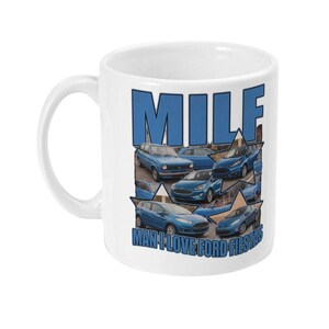 May include: A white ceramic mug featuring a collage of blue Ford Fiesta cars arranged within star shapes. The text MILF is printed in large blue letters at the top, and the text MAN I LOVE FORD FIESTAS is printed in blue letters at the bottom.